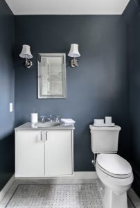 Newly renovated small bathroom with bold blue wall color and classic tile floor.