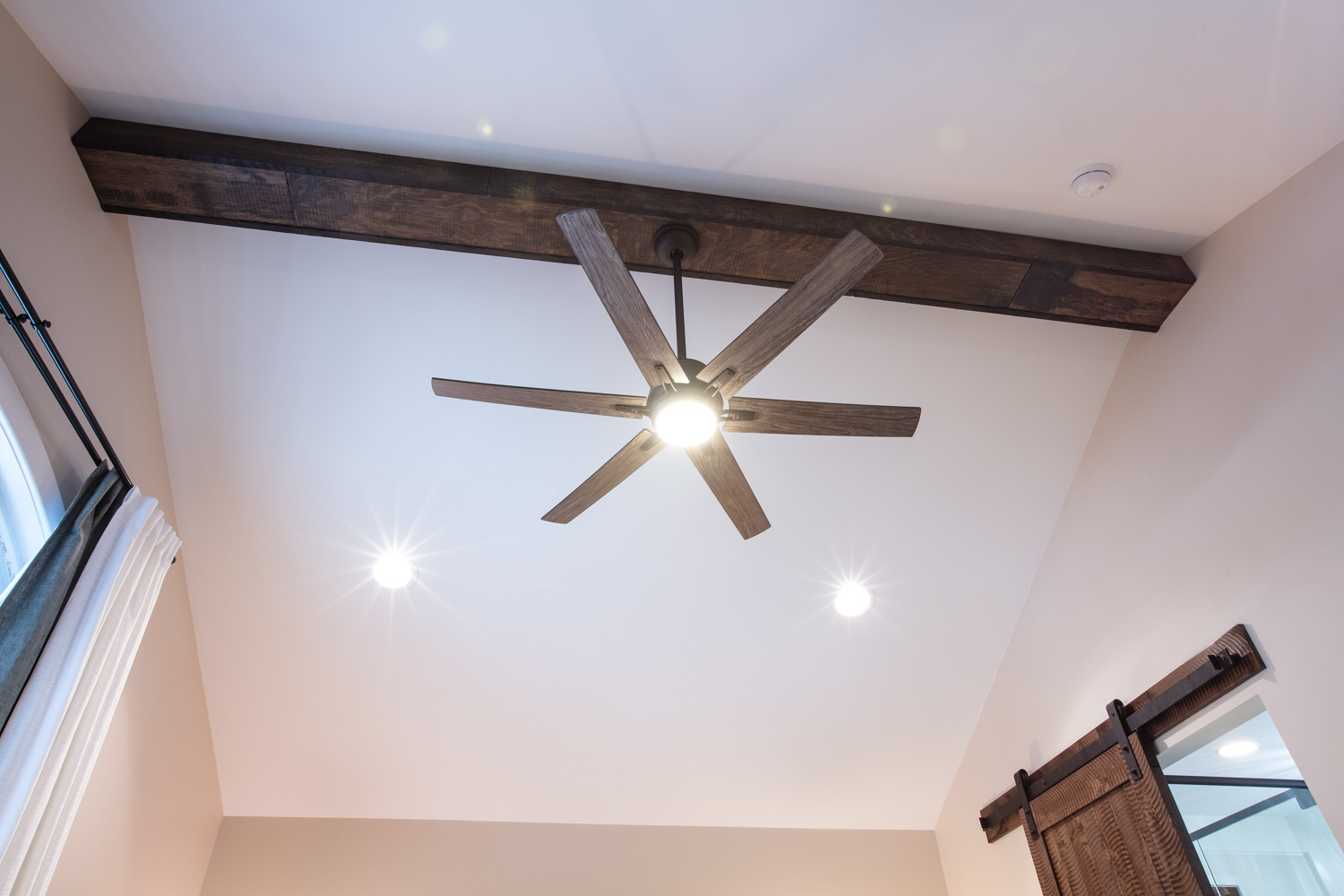 High ceiling with can lights and a ceiling fan in a bedroom remodel.