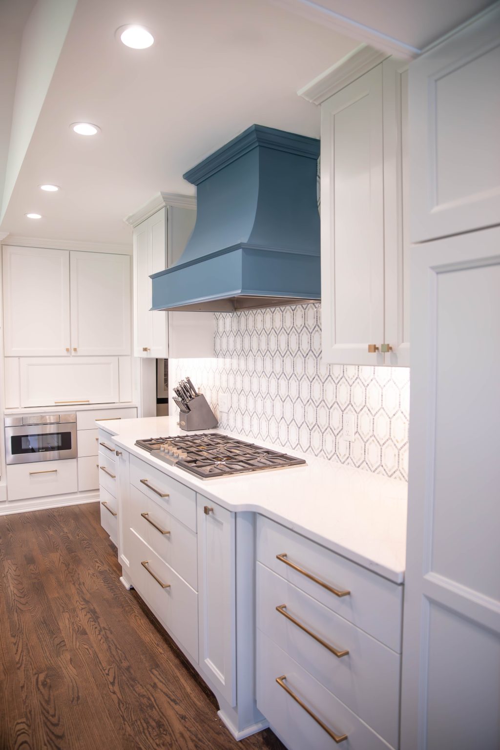 Blue oven hood in a newly remodeled Ottawa Hills kitchen with all white cabinetry and countertops