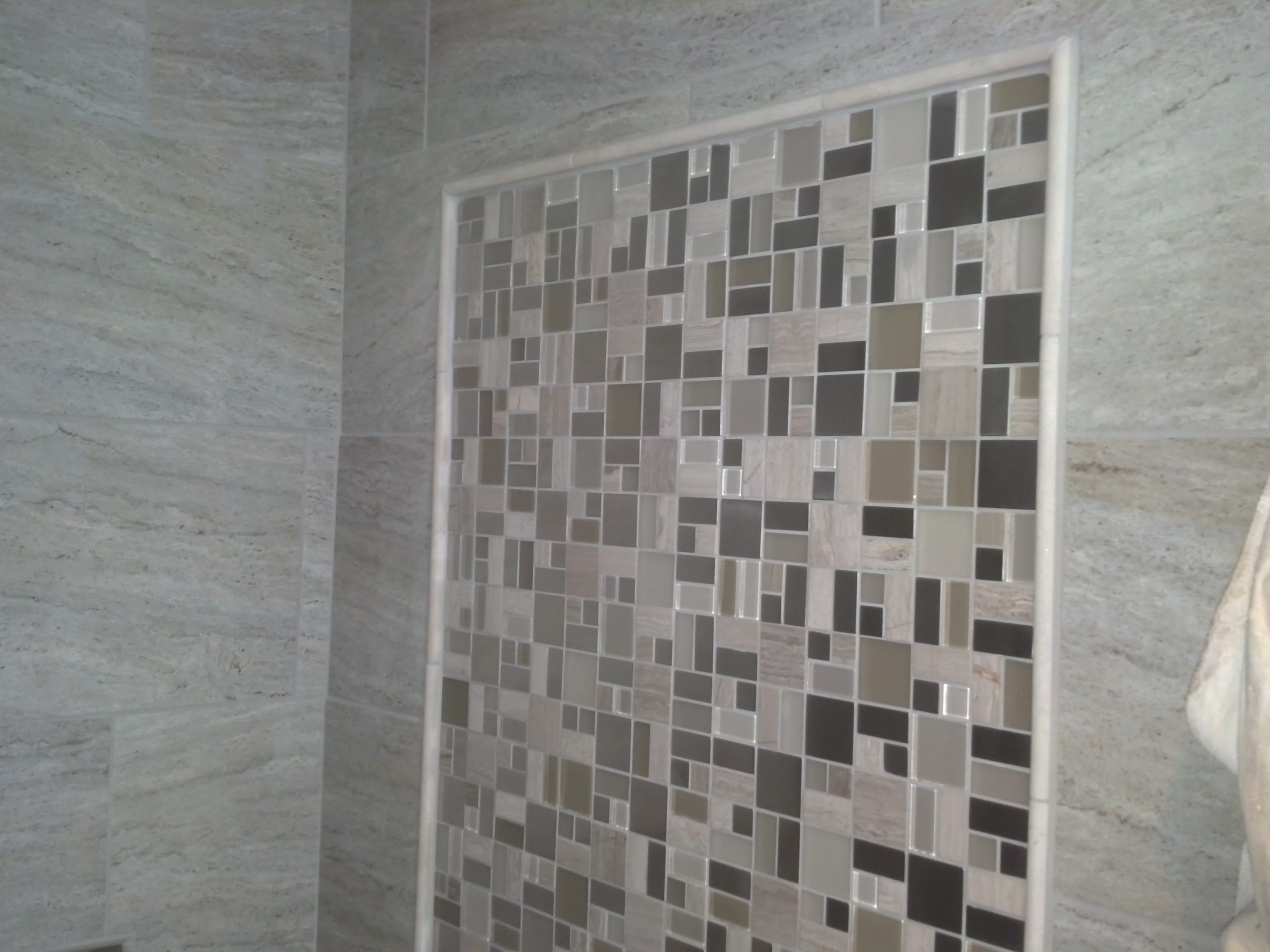 Updated tile wall in a modern, gray bathroom. 