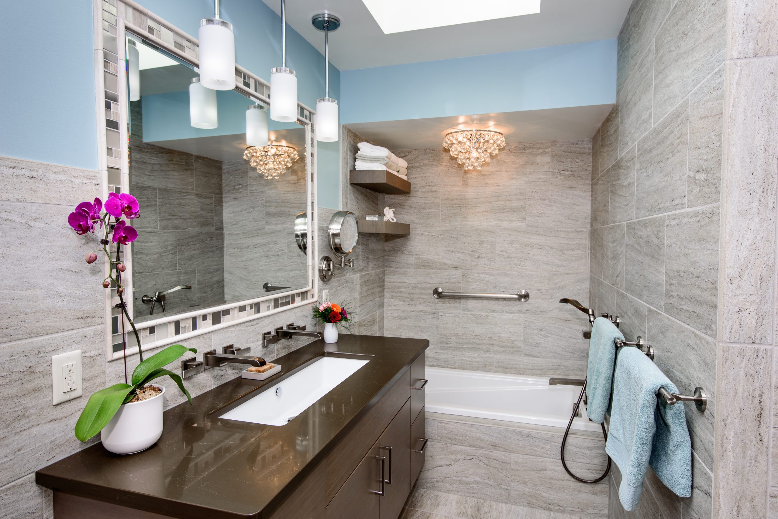 Modern, updated bathroom with blue accent walls and brown vanity. 