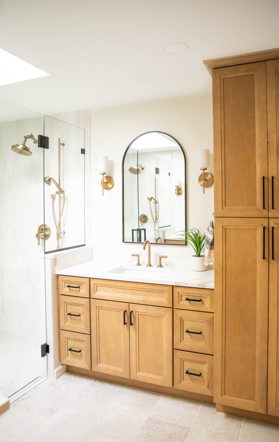 Natural wood vanity with white countertop attached to tall storage cabinet installed by Sylvania bathroom remodeler