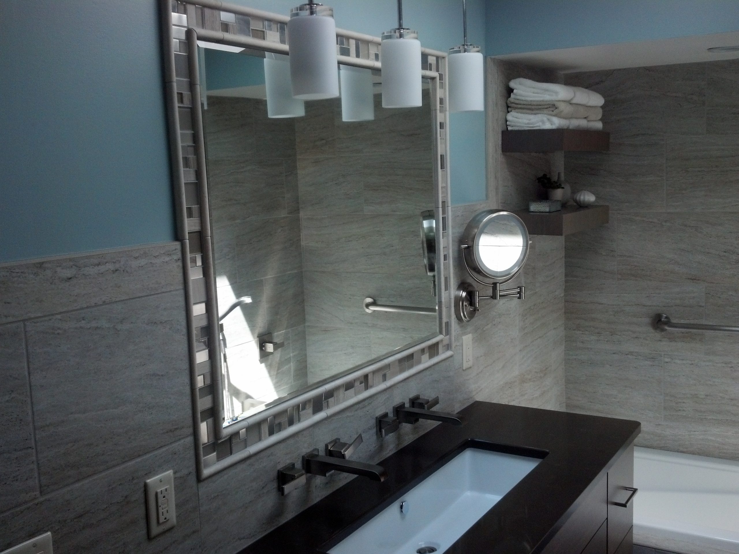 Close up of a remodeled bathroom with a floating vanity and custom lighting. 